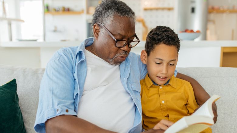A grandfather and his grandchild reading a book together.