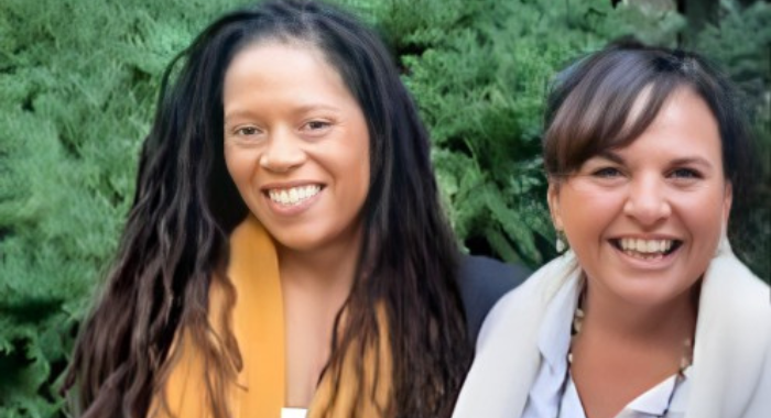 Two women, Melanie and Kristen, in front of bushes