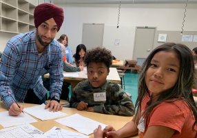 A tutor working with two young learners at a table during a homework help session.