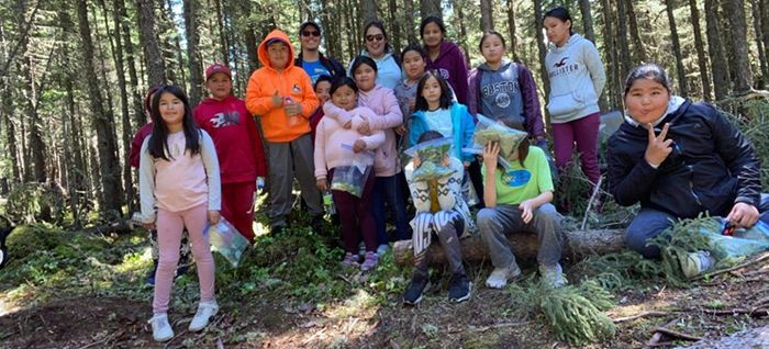 A group of kids in front of tall pine trees