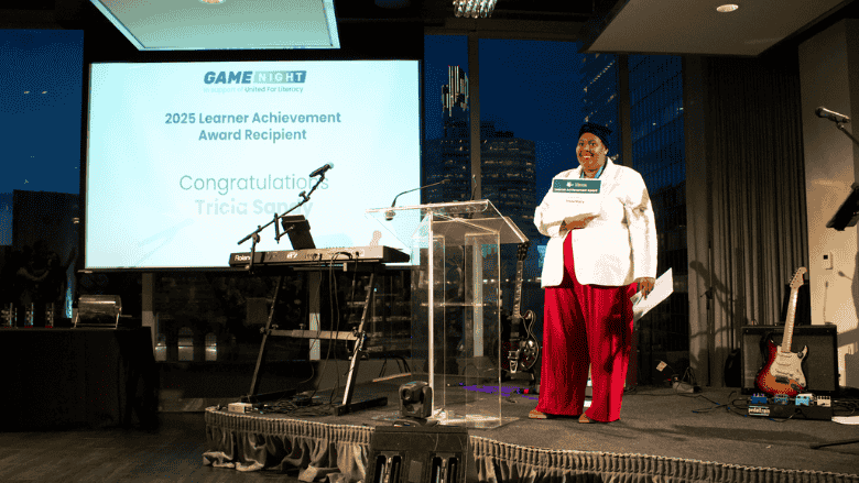 Tricia Sandy, standing on the stage, while she is being introduced to receive the award.