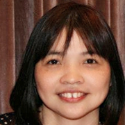 A woman with brown hair and brown eyes. She is smiling.