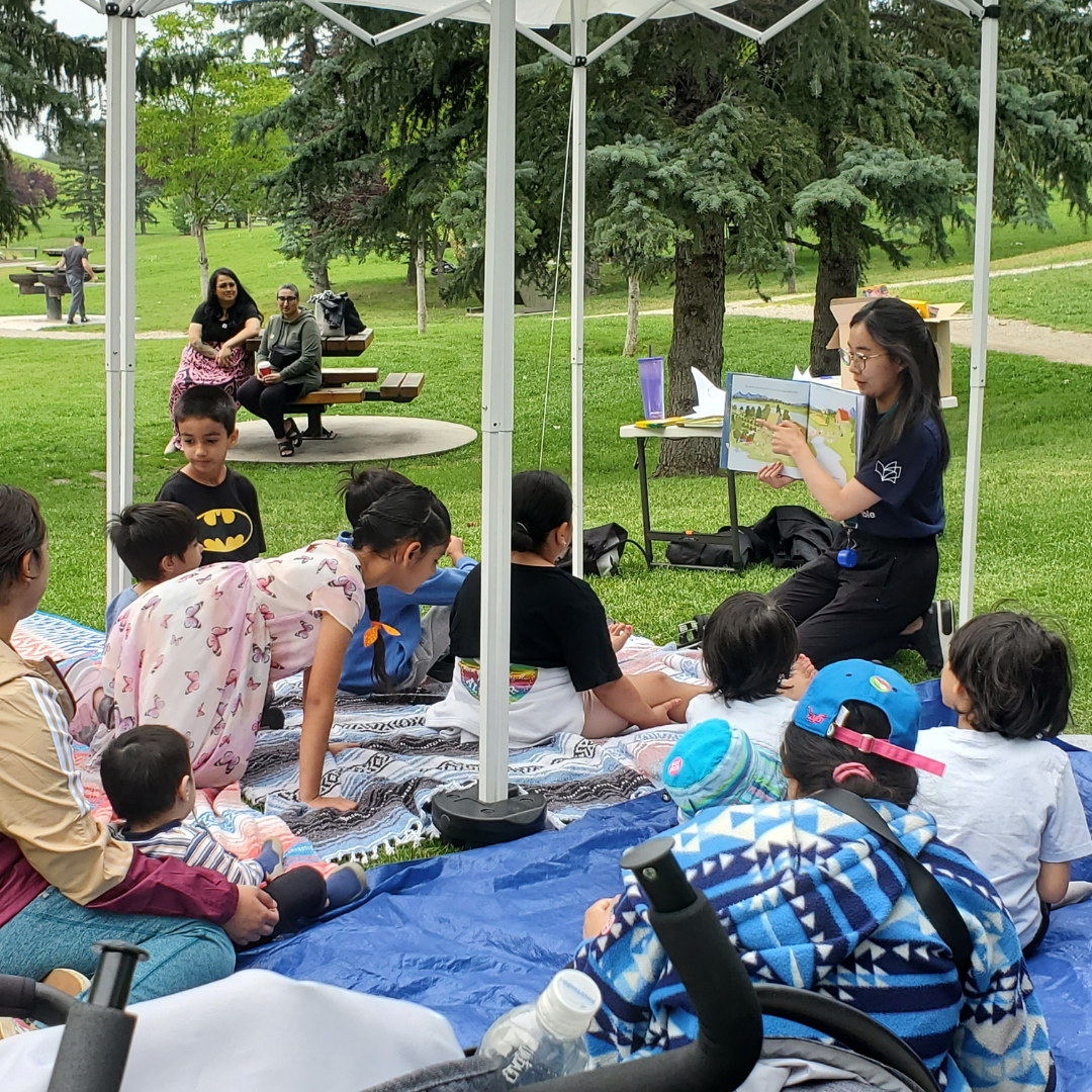A volunteer reading a book under a reading tent